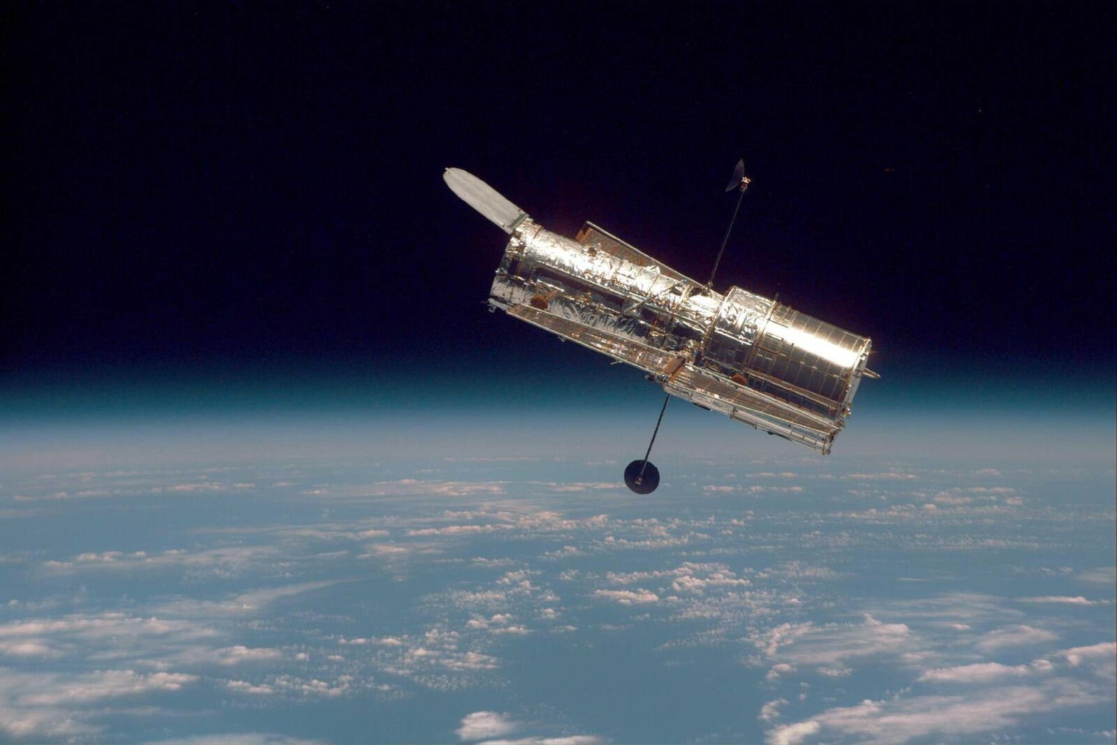 O Telescópio Espacial Hubble flutuando diante da curva da Terra